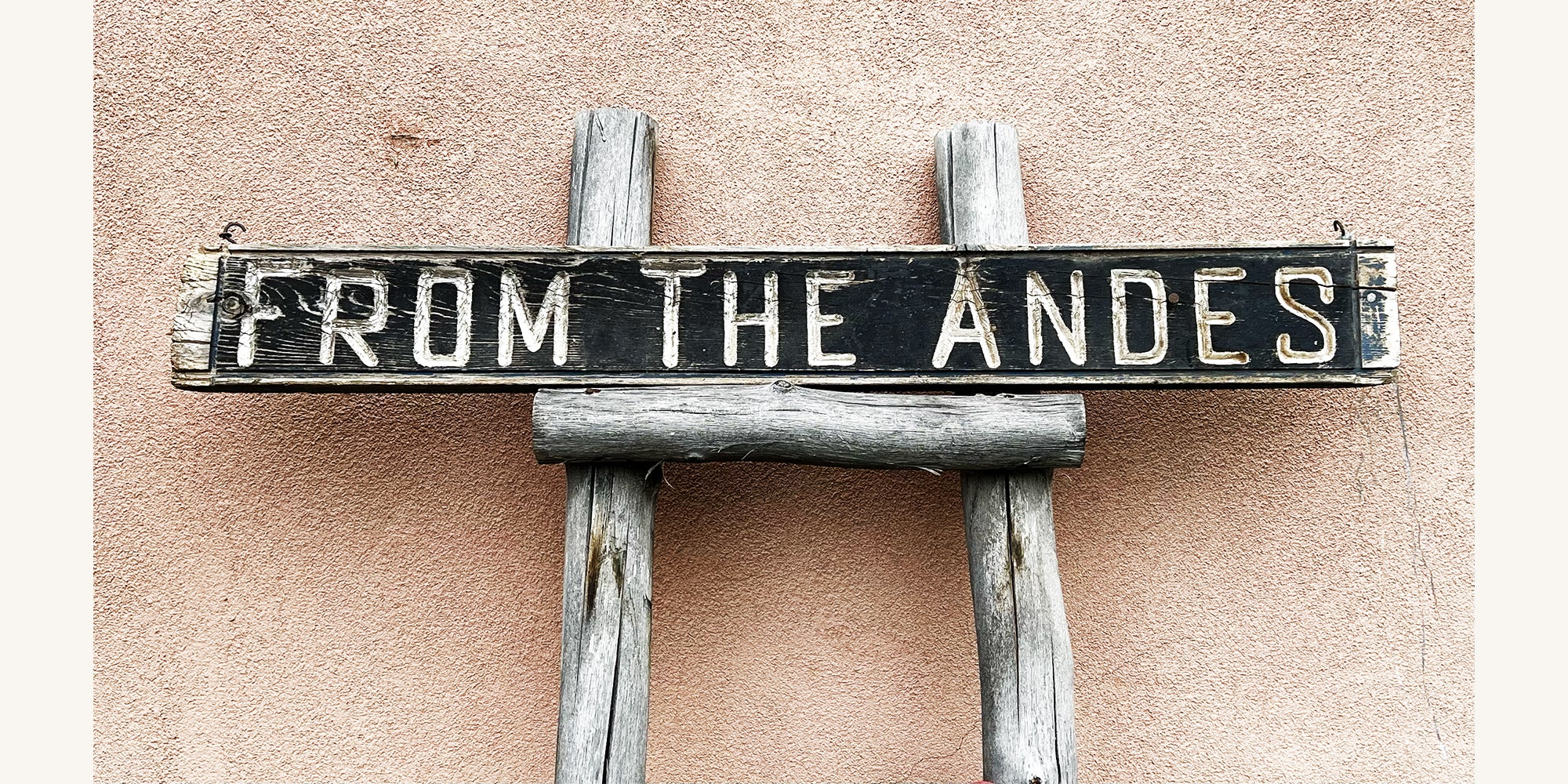Wooden sign with 'From the Andes' text on an adobe wall