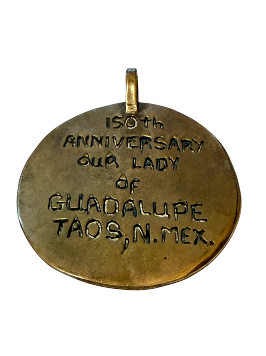 Reverse of pendant inscribed 150th Anniversary Our Lady of Guadalupe Taos N. Mex.